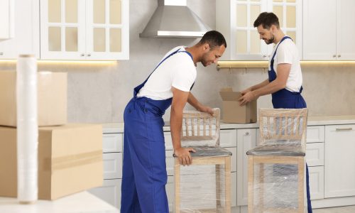 Male movers with chairs in new house